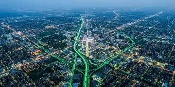 Aerial view of a city at dusk, showing intricate patterns of green and blue lights, representing the evolving landscape of celebrity influence and digital connections.